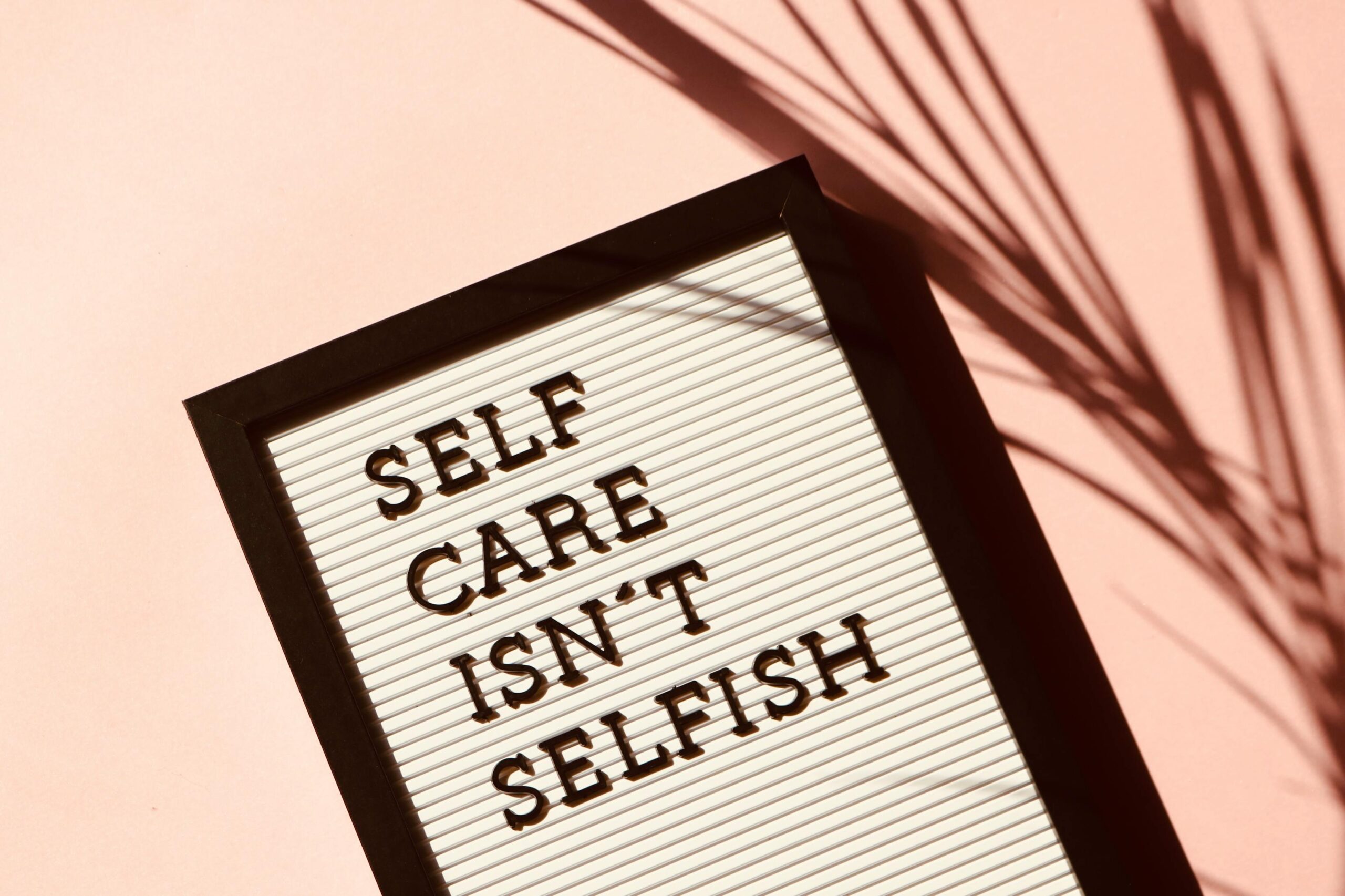 Motivational Quote Generator 1 Letter board displaying 'Self Care Isn't Selfish' with artistic shadow on pink background.