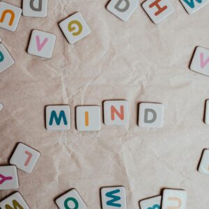 Close-up of scattered letter tiles spelling 'mind' on crumbled paper background.