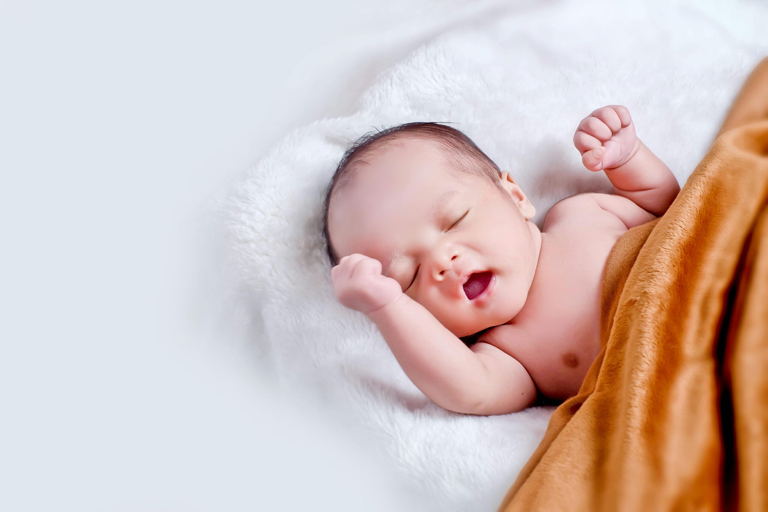Baby Face Predictor – AI Baby Generator 3 A peaceful sleeping infant wrapped in a soft, warm blanket on a cozy white surface.